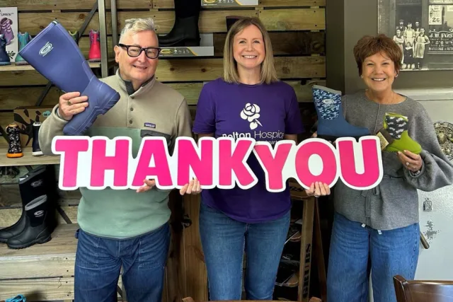 The Grubs and Bolton Hospice team holding a giant “THANK YOU” sign with donated Grubs wellington boots in the Grubs shop
